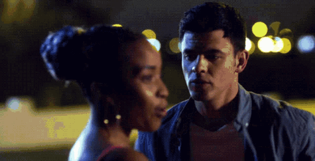 a man and a woman are looking at each other in a dark room