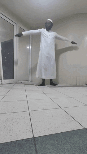 a man in a white robe stands in a hallway