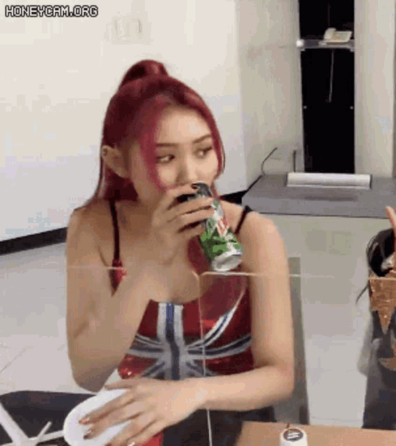 a woman with red hair is drinking from a can of mountain dew .