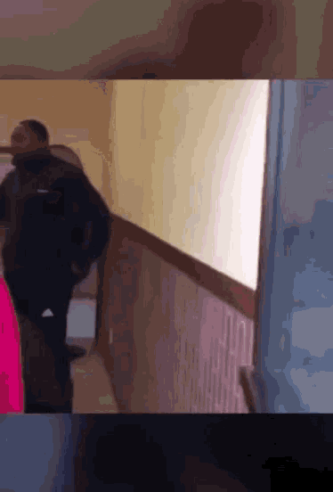 a man is walking down a hallway with a backpack on