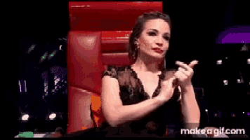 a woman is sitting in a red chair giving a thumbs up .
