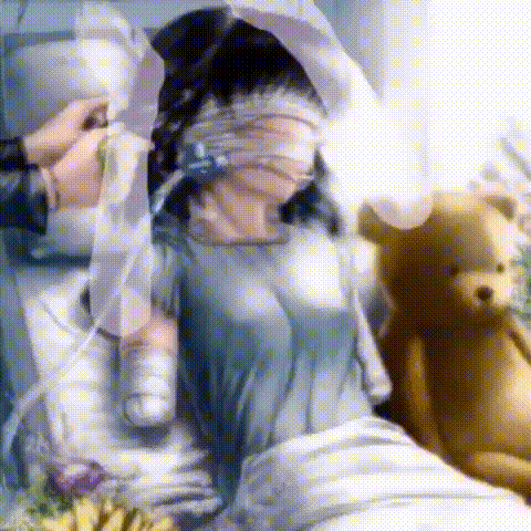 a woman is laying in a hospital bed with her eyes covered and a teddy bear in the background .