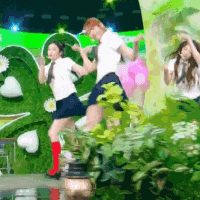 a group of people are dancing in front of a green wall