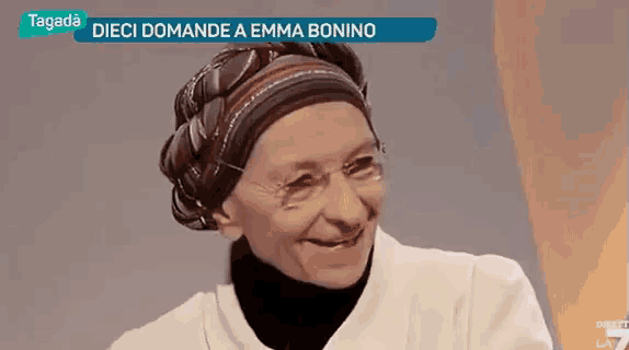 a woman wearing a headband and glasses is smiling in front of a tv screen that says tagada