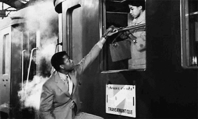 a man in a suit is reaching out to a woman in a train car .