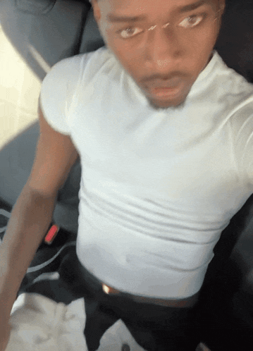 a man in a white shirt is taking a selfie in a car