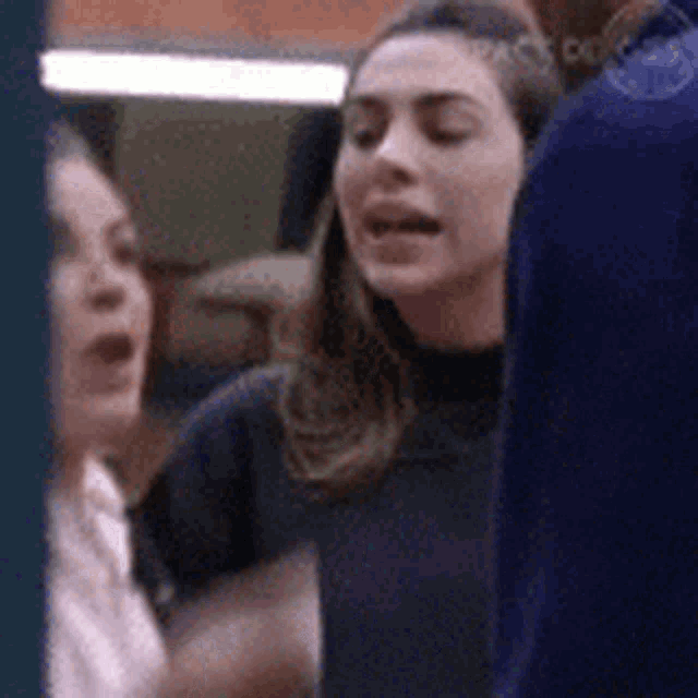 a group of women are standing next to each other and one of them is making a funny face .