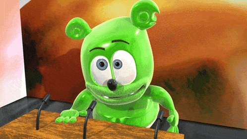 a green gummy bear is sitting at a podium