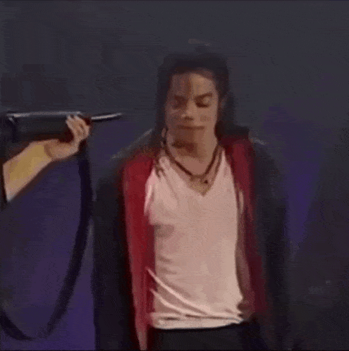 a man in a white shirt and red jacket is standing on a stage .