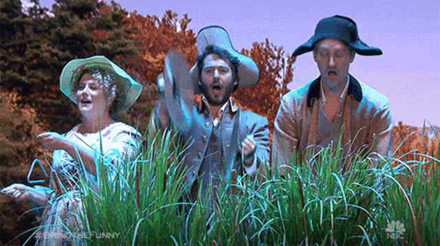 a group of people are standing in a field of grass .