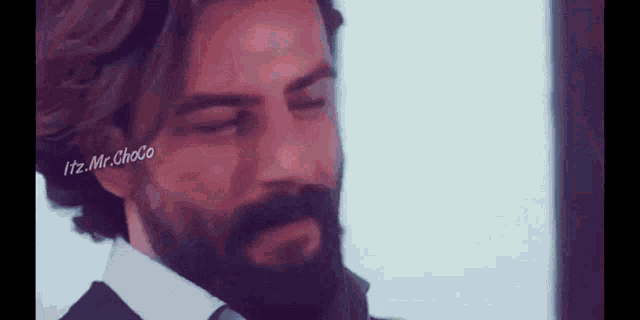 a man with a beard is wearing a suit and tie .