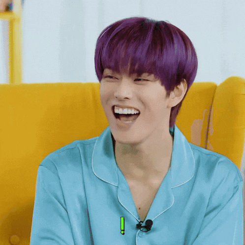 a young man with purple hair and a blue shirt is laughing