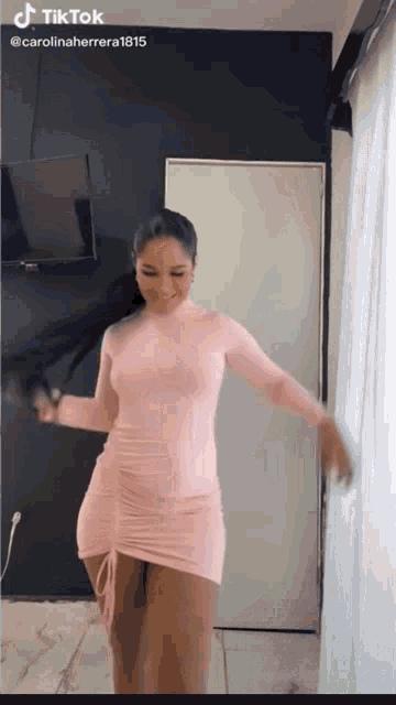 a woman in a pink dress is dancing in front of a door