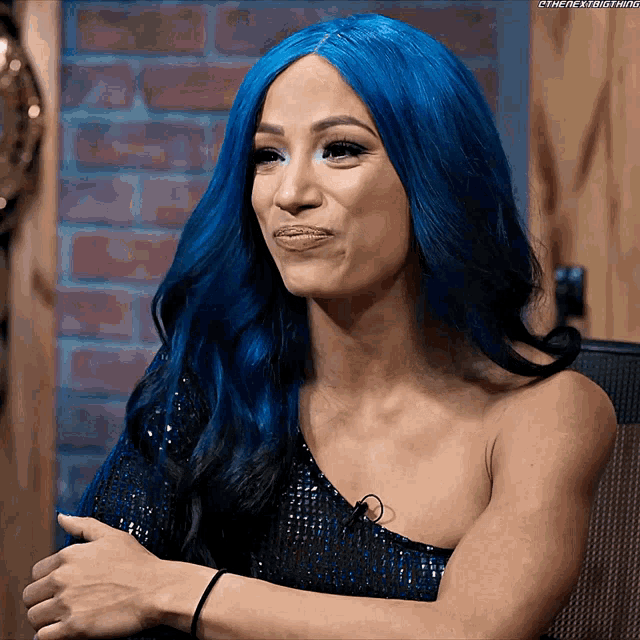 a woman with blue hair is sitting in a chair and smiling