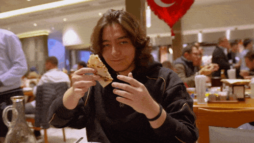 a young man is eating a slice of pizza