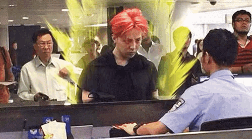 a man with red hair is being checked at an airport by a police officer