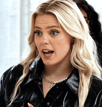 a blonde woman wearing a black leather jacket and a pearl necklace