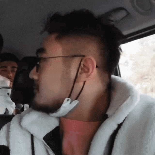 a man wearing glasses and a mask is sitting in the back seat of a car