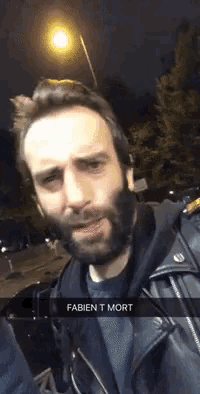 a man with a beard is wearing a leather jacket and has the word fabien t mort written on his face
