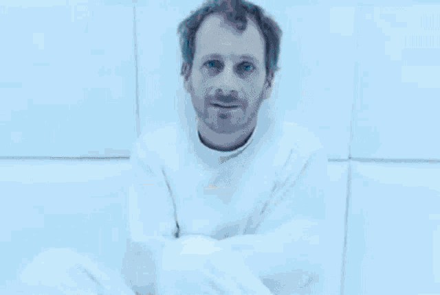 a man is wrapped in a white blanket and is looking out a window