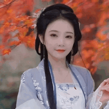 a woman in a traditional costume is standing in front of a tree with leaves .