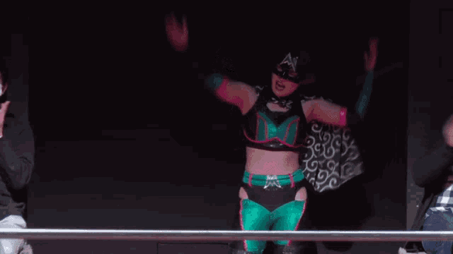 a man wearing a mask watches a female wrestler