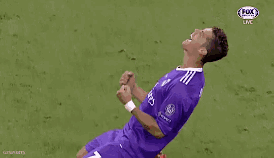 a soccer player in a purple jersey is kneeling on the field and celebrating a goal .