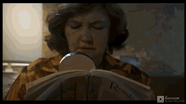 a woman looks at herself in a mirror while reading a book titled rough