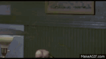 a man in a yellow jacket is covering his face with his hand in a dark room .