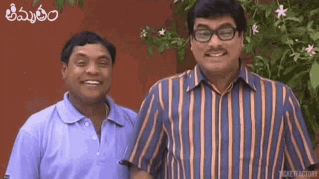 two men in striped shirts are standing next to each other and smiling for the camera .