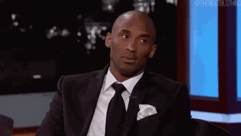 a man in a suit and tie is sitting in a chair and looking at the camera .