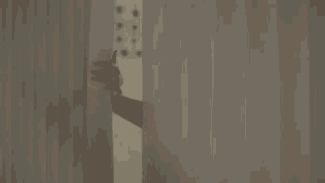 a woman is peeking out from behind a curtain in a bathroom .