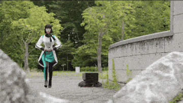 a woman in a green and white outfit is walking down a path in a park