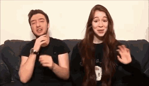 a man and a woman are sitting on a couch and talking to each other .