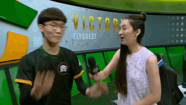 a man and a woman shake hands in front of a screen that says victory flyquest
