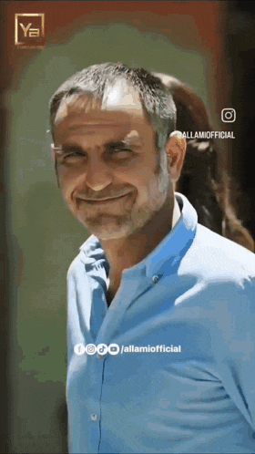 a man with a beard wearing a blue shirt is smiling and looking at the camera
