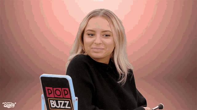 a woman sitting in front of a mirror with pop buzz written on it