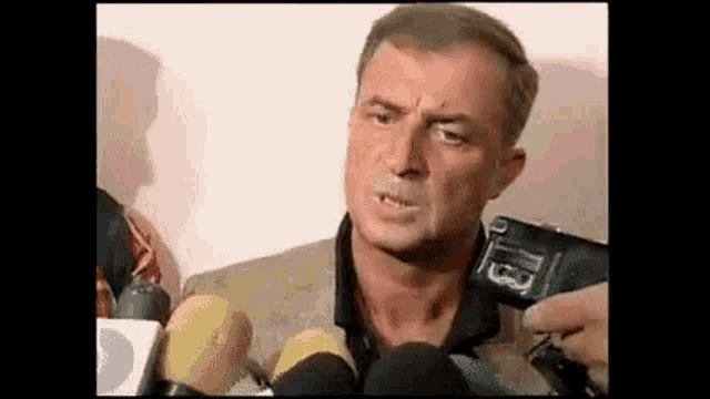 a man is standing in front of a bunch of microphones .