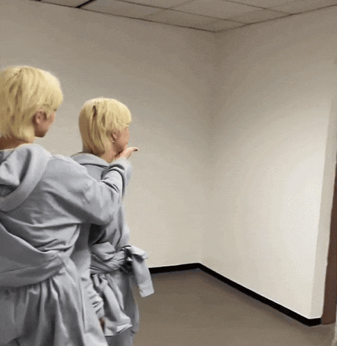 a couple of people standing in an empty room pointing