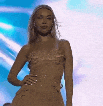 a woman in a dress is standing on a stage with her hand on her hips .