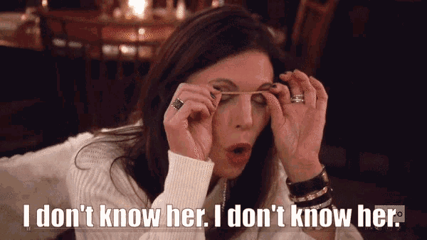 a woman in a white sweater is holding a rubber band to her eye and says i don 't know her
