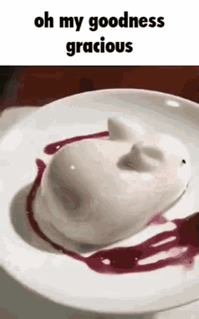 a white dessert with a face on it is on a plate with a sauce .