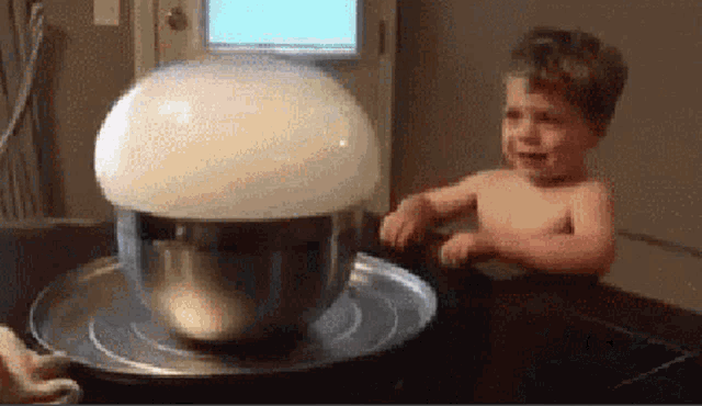 a shirtless child is sitting in front of a bowl of bubbles .