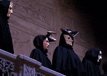 a group of people wearing hooded capes and masks are standing on a balcony