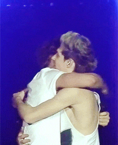 two men hugging each other on a stage with a blue background