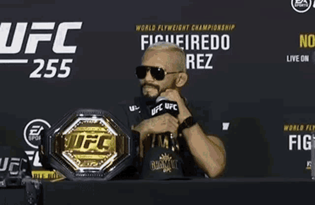 a man is sitting at a table with a ufc belt on it .