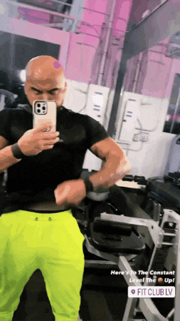 a man is taking a picture of himself in a gym with a pink background