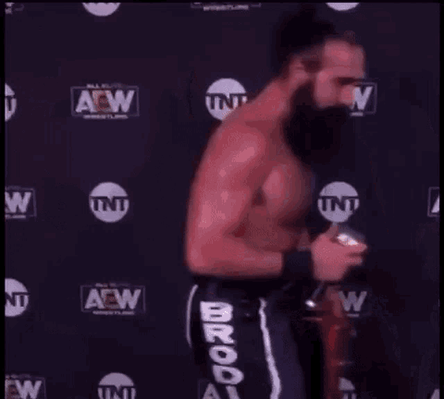 a wrestler with a beard is holding a microphone and saying the audacity .