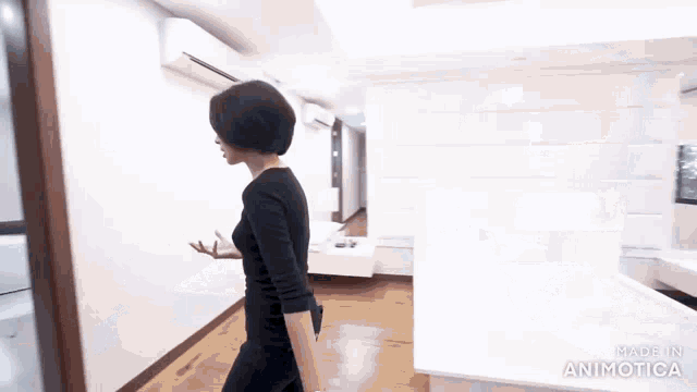 a woman in a black dress is walking down a hallway with the words made in animatica at the bottom
