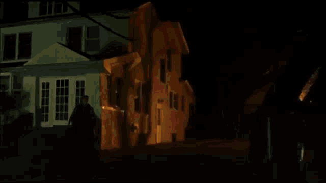 a man is standing in front of a building with a fire coming out of it .